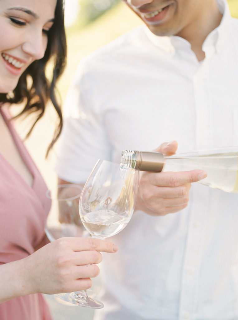 a man pours his fiancé a glass of white wine 