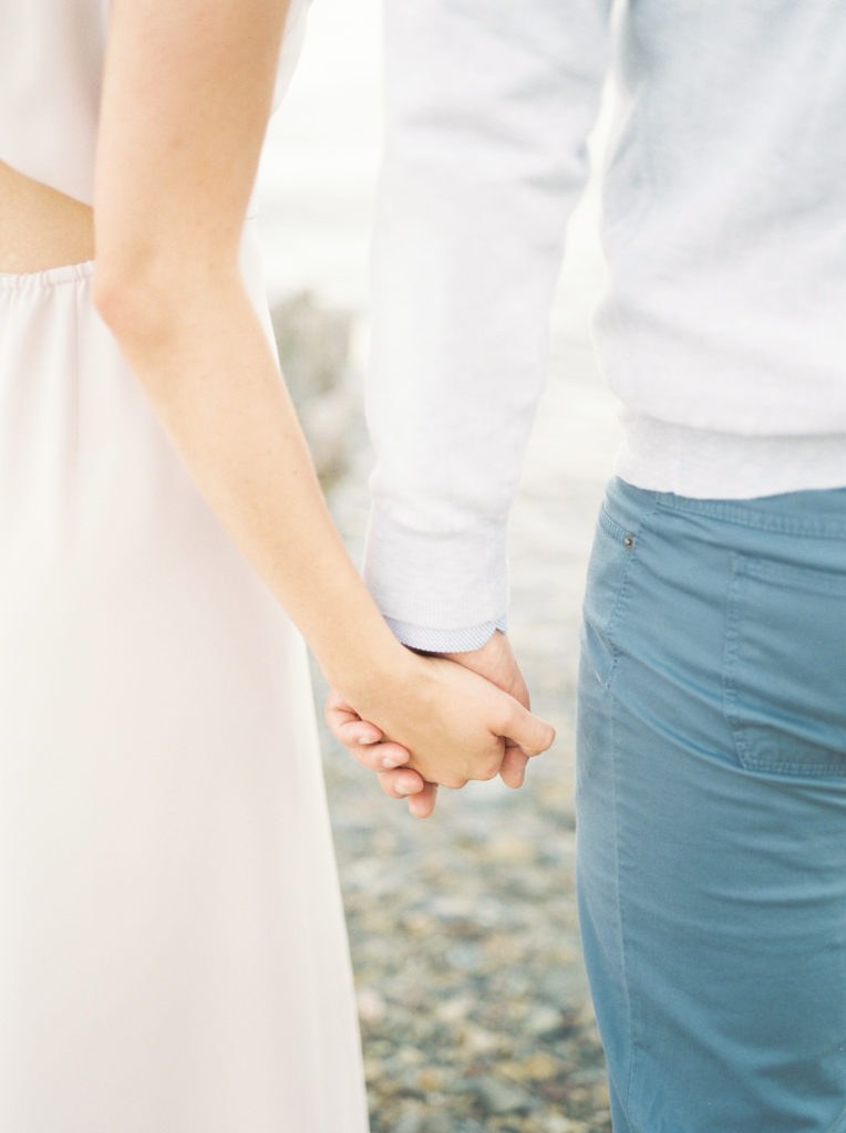 an engaged couple hold hands at Kelowna Lake 