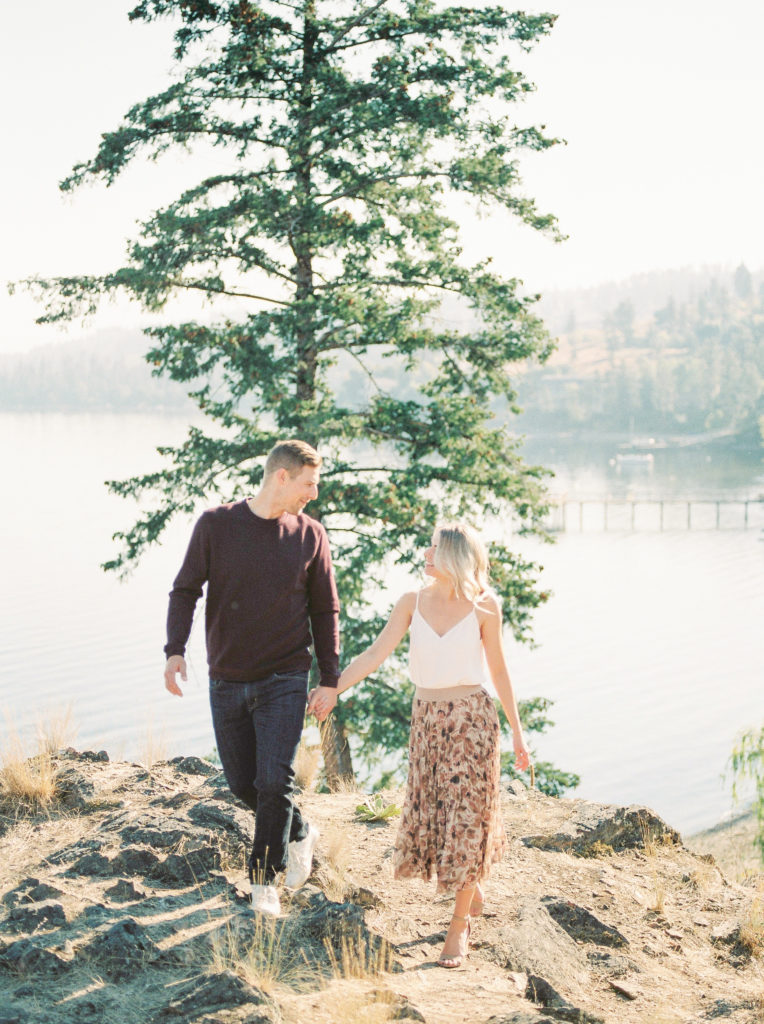 a engaged couple walk along a lake view cliff in Kelowna 