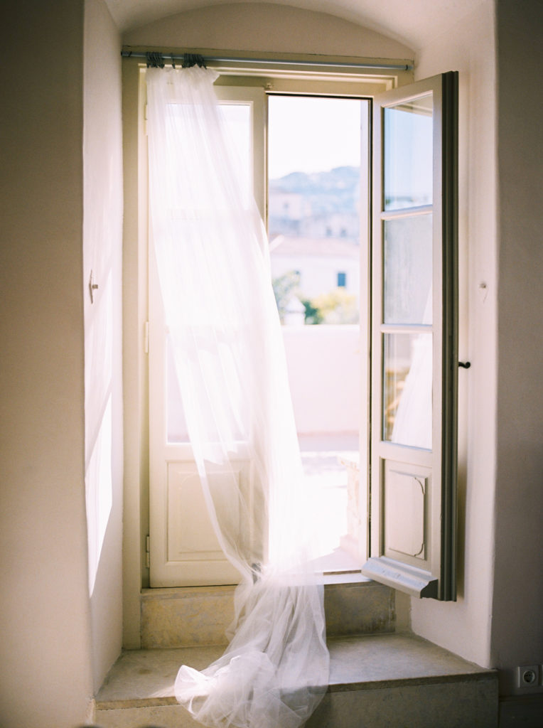 an open villa bedroom window with a sheer curtain blowing in the wind 