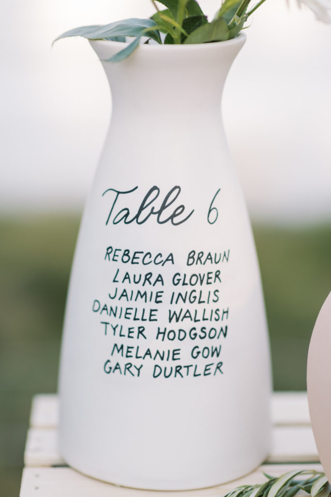 a white vase seating chart at a wedding reception 