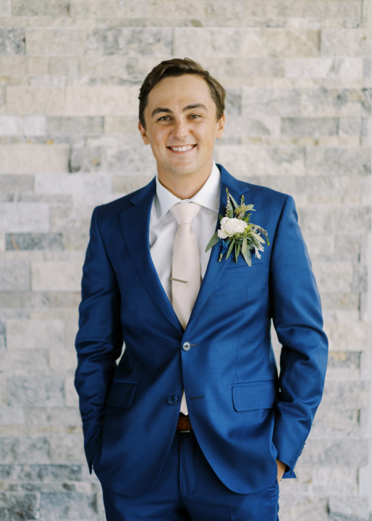 a groom in a navy blue suit with a pink tie