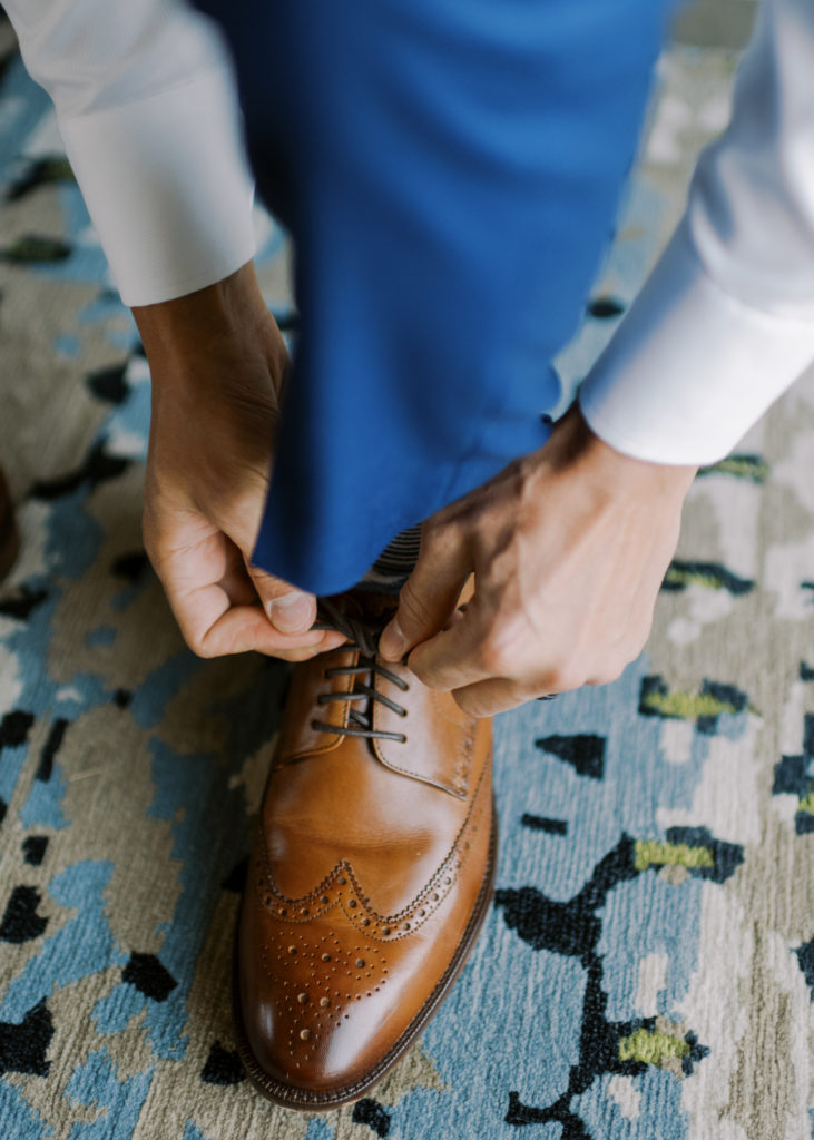 a groom tying his brown leather shoes