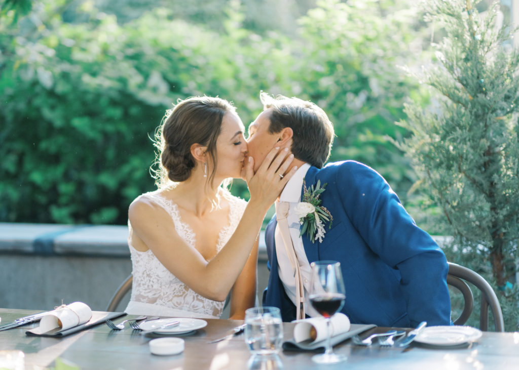 a bride and groom kiss at their sweetheart table 
