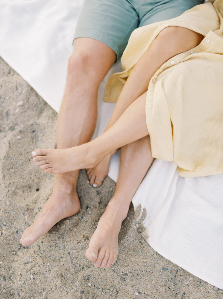 an engaged couples bare feet in the sand 