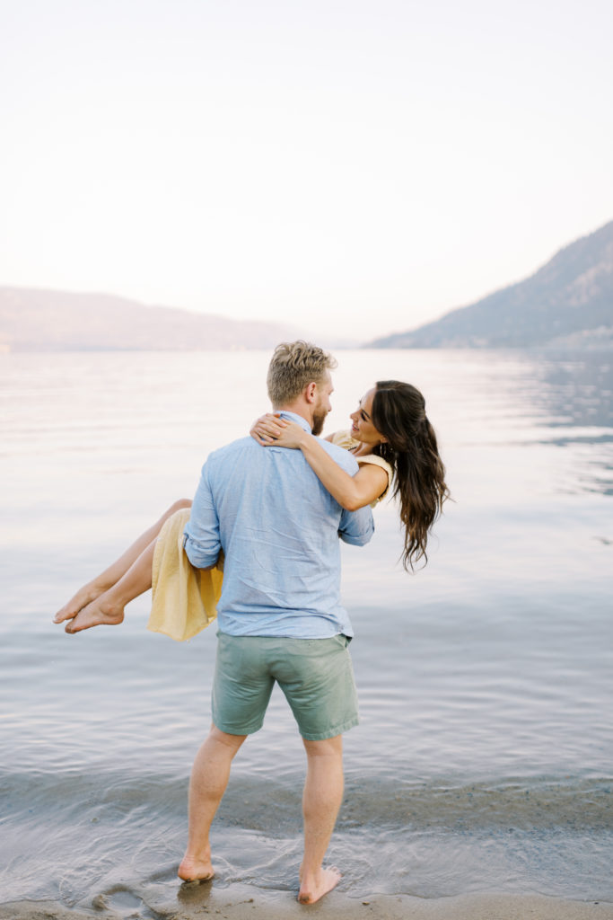 a man spins his fiancé for their Kelowna beach engagement photos 