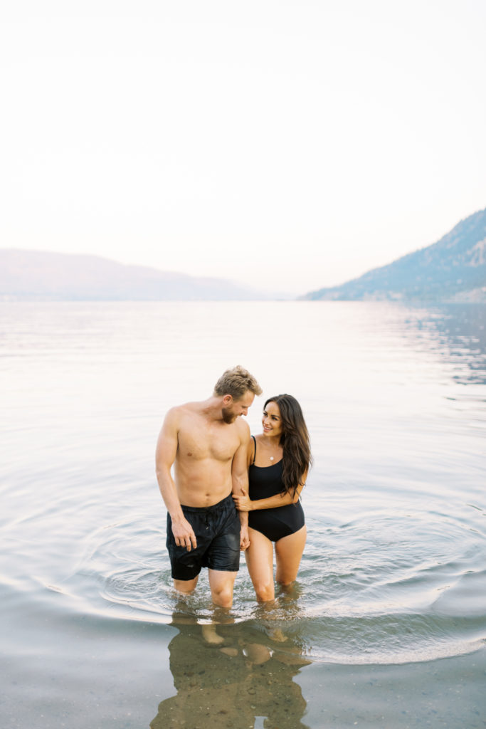 a couple walk in the lake at their Kelowna beach engagement 