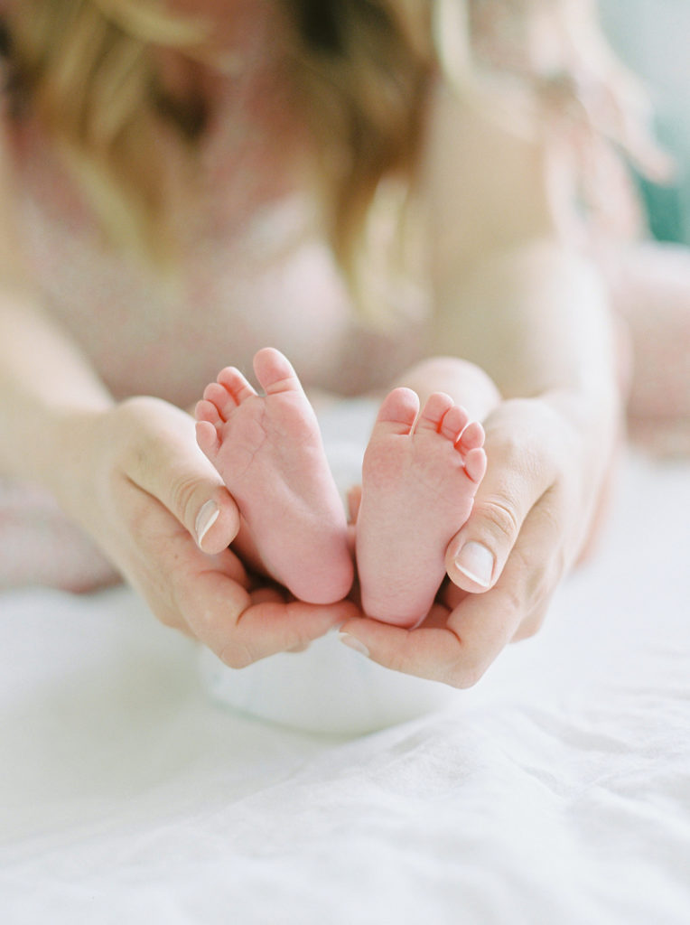 mom holds newborn sons feet 