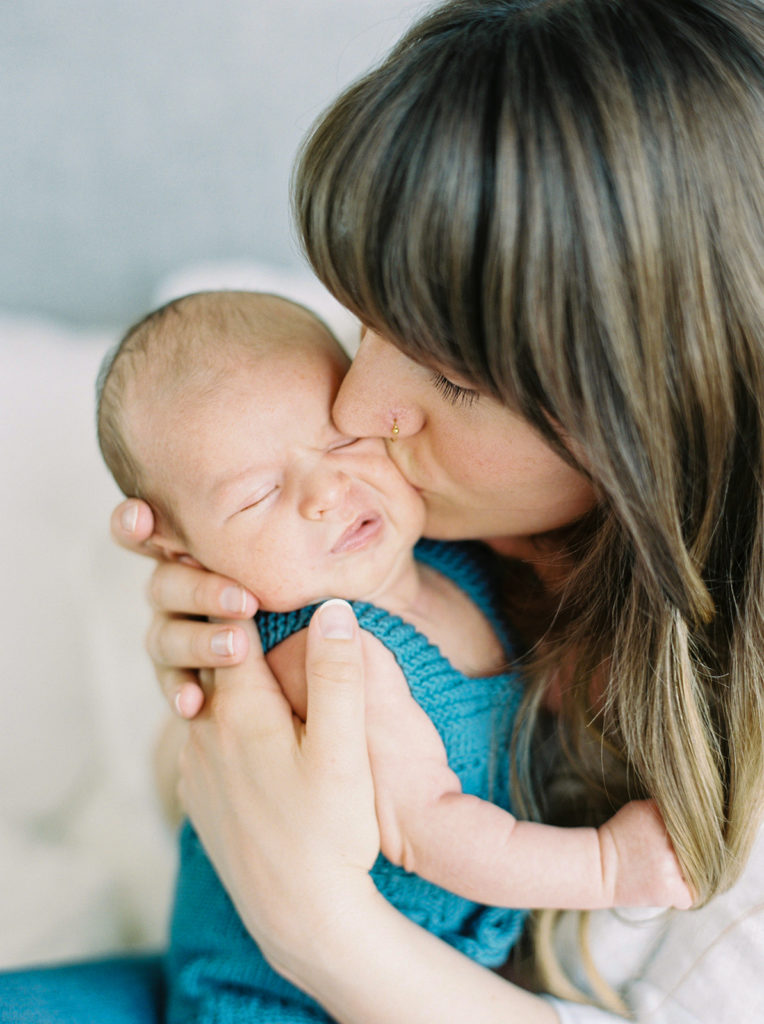 mom kisses newborn son on the cheek 