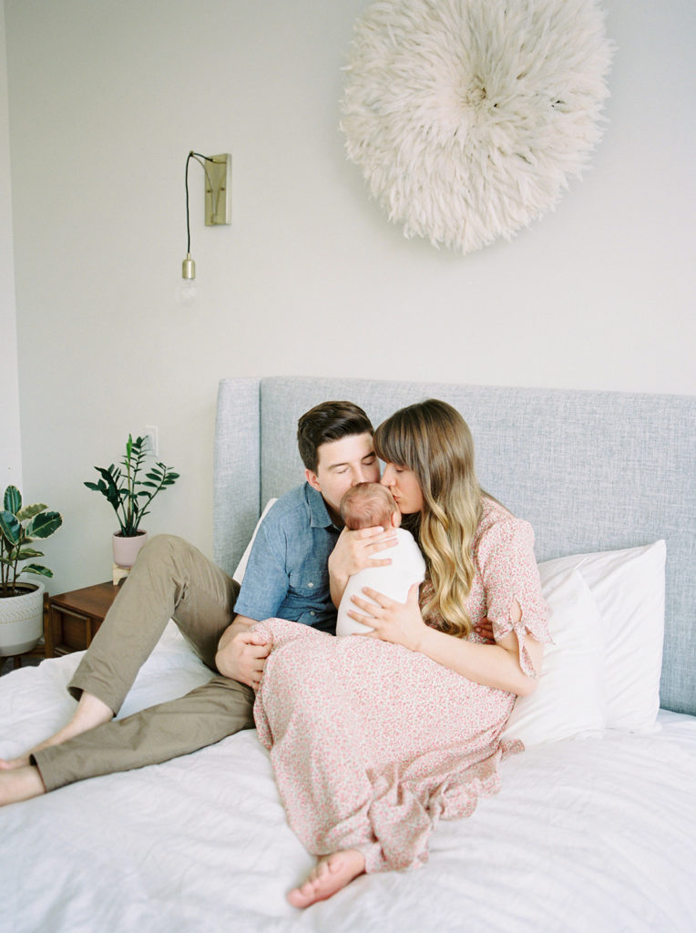 mom and dad kiss baby at Kelowna in home newborn session 