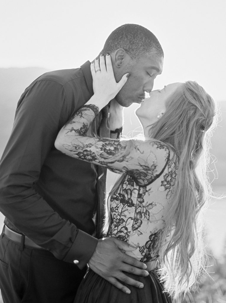 a black and white portrait of a bride and groom kissing 