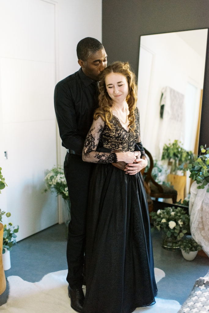 a groom helps his bride into her wedding dress