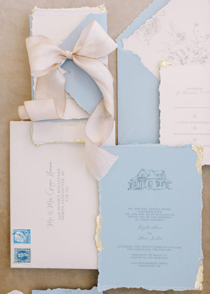 blue and ivory wedding invitation tied with a satin bow 