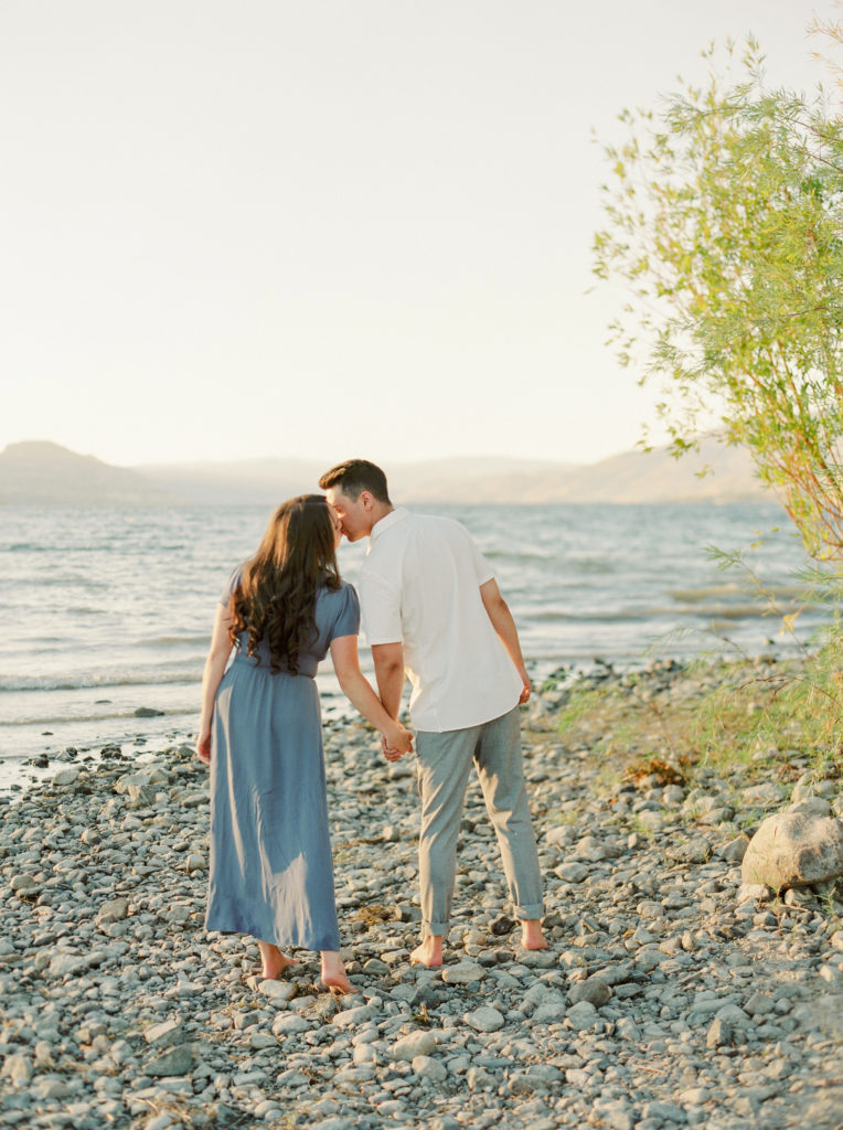 an engaged couple kiss on a beach in the Okanagan 