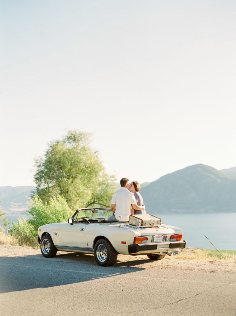 a couple kiss while sitting in a classic car in Naramata 