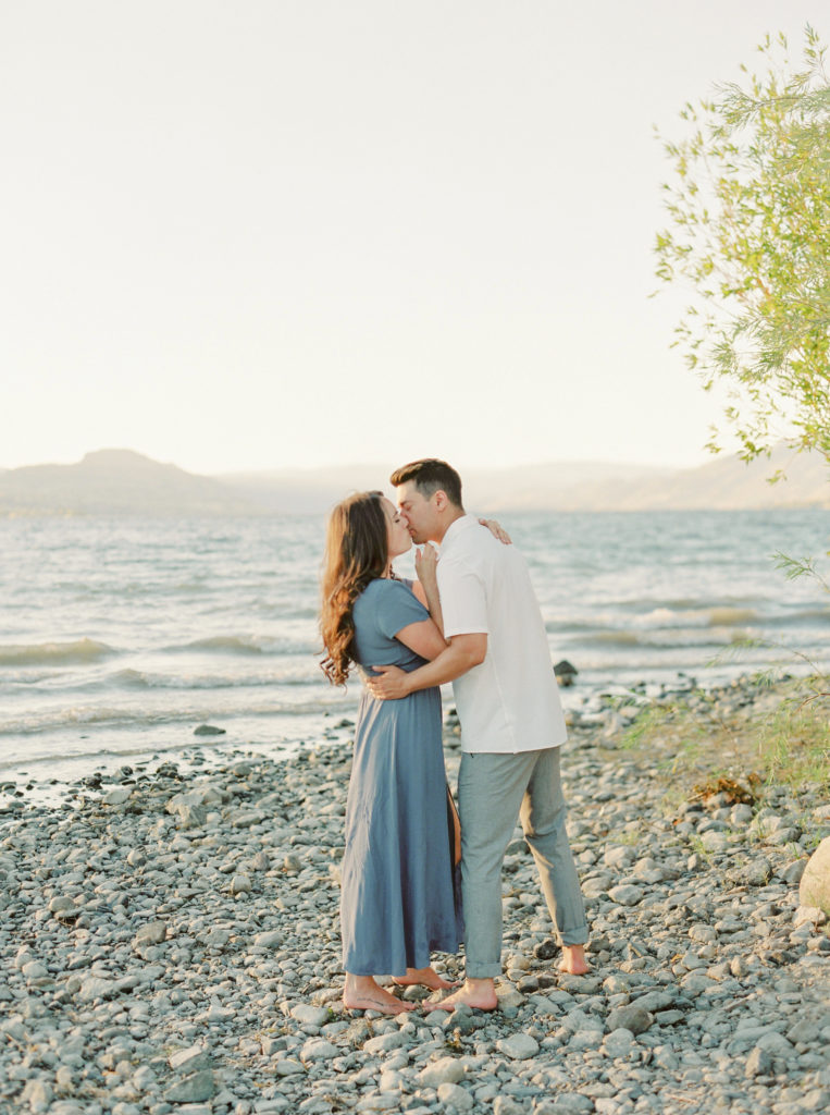 a couple kiss on a beach for their Okanagan couples session 
