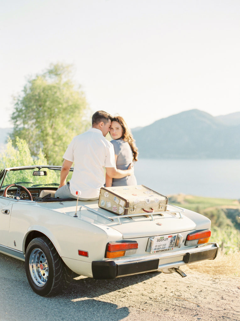 a couple pose in a Fiat for their Okanagan couples session 